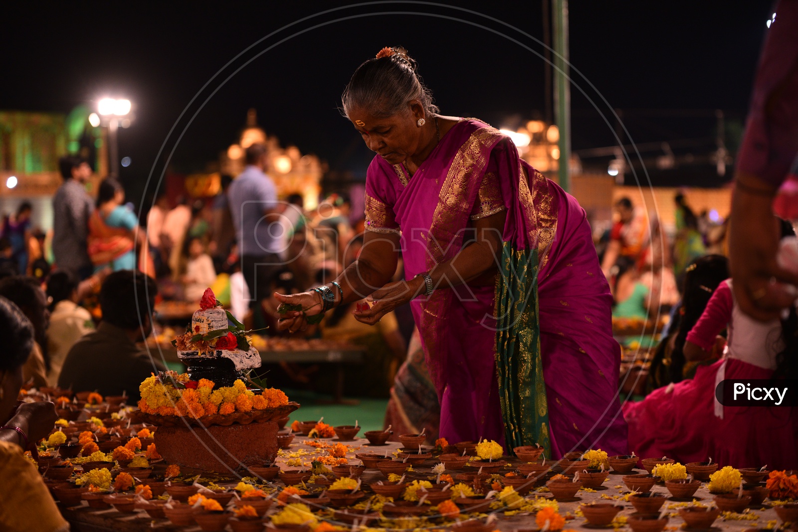 A woman decorates Hindu god, Shiva Linga Idol