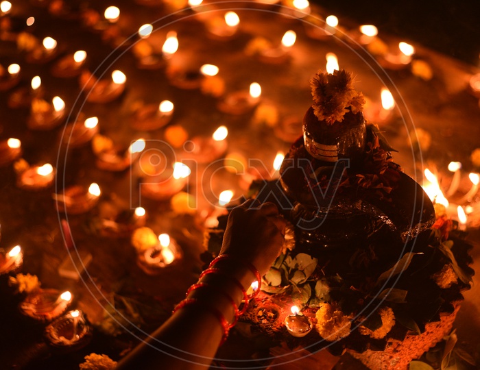 A woman decorating Shiva Lingam