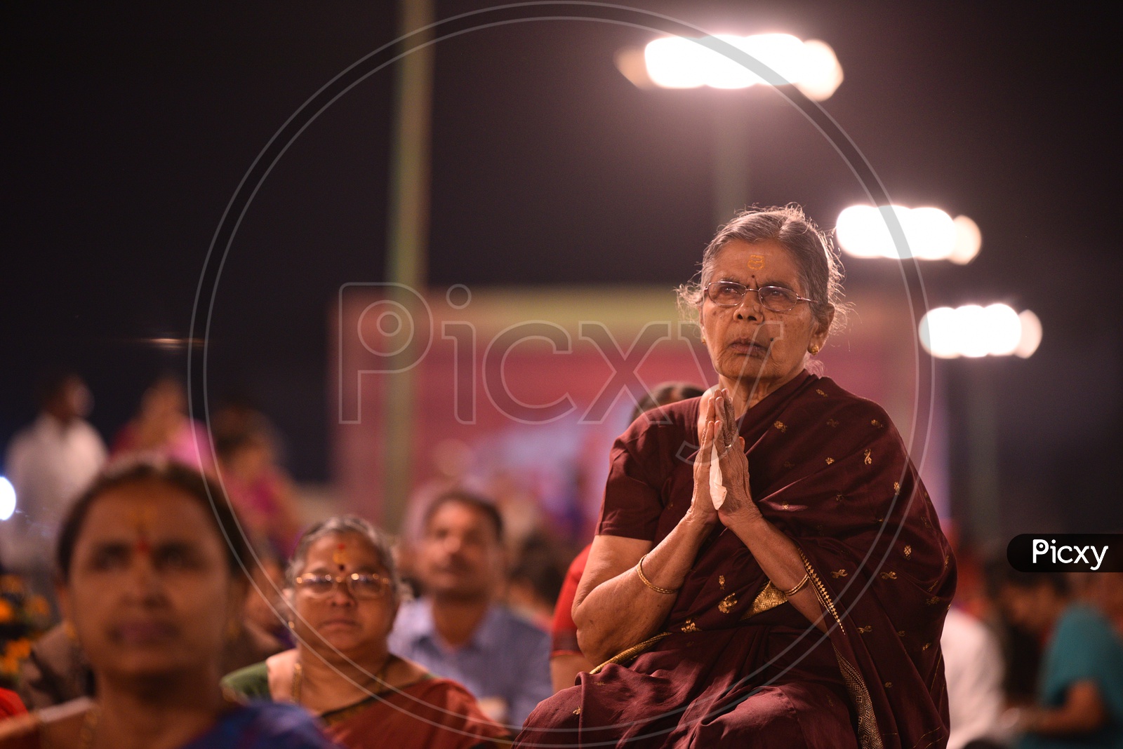 An elder woman praying at Koti deepotsavam