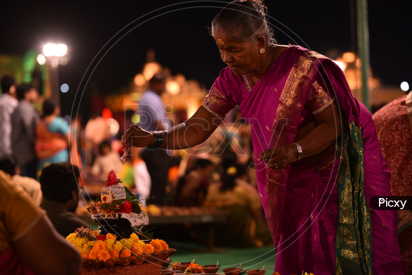 A woman decorates Hindu god, Shiva Linga Idol
