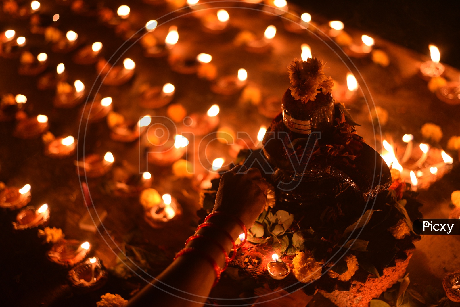 A woman decorating Shiva Lingam