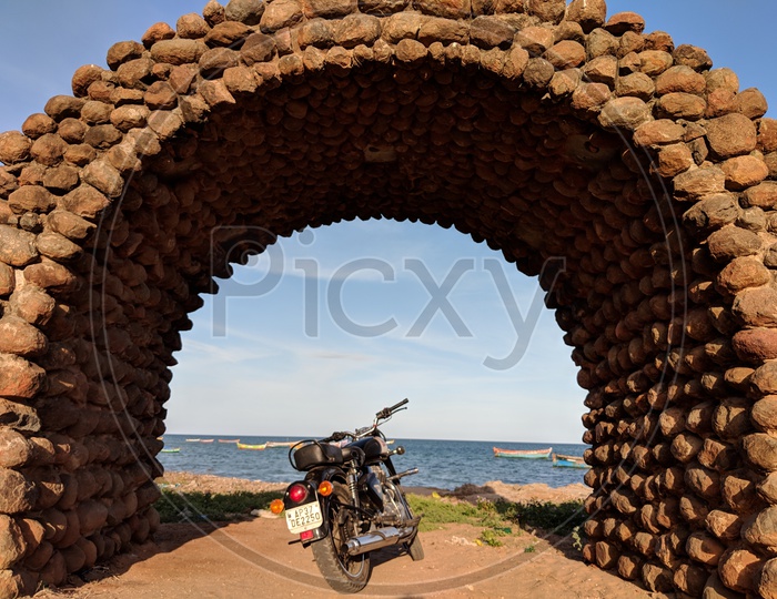 Royal Enfield Bike under a Stone Shade by the beach