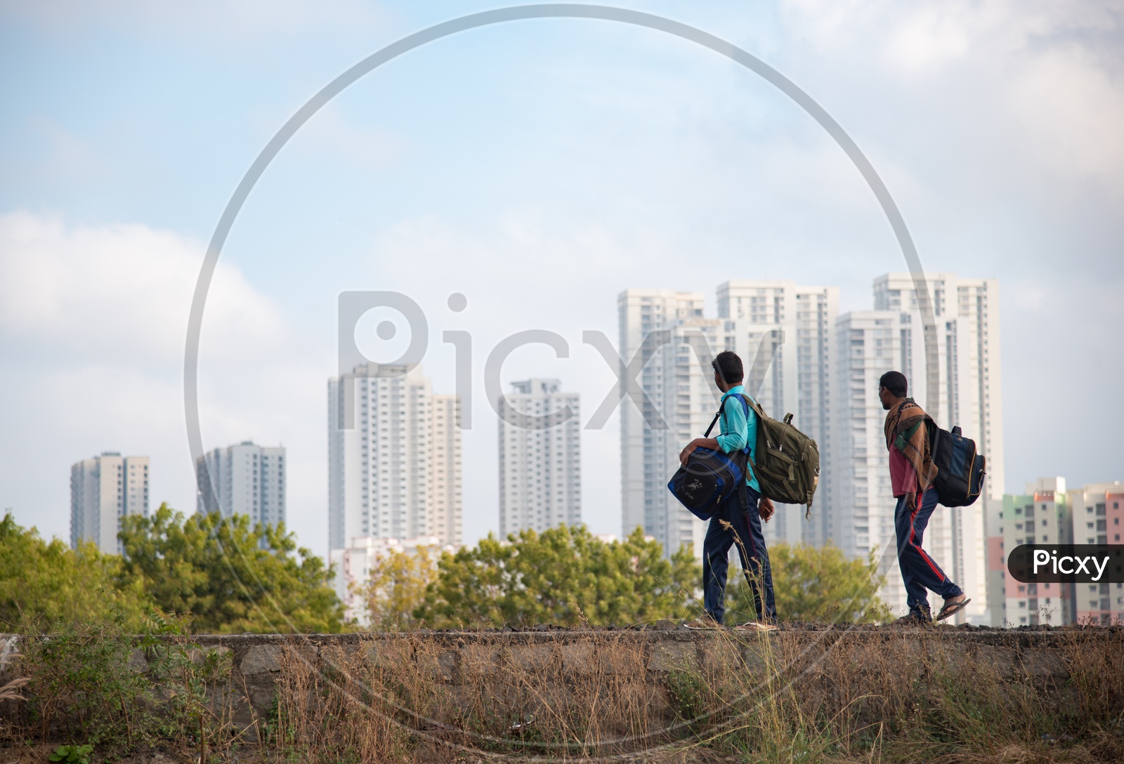 two construction workers walk on a small wall across Railway tracks near MMTS, Hitech City station