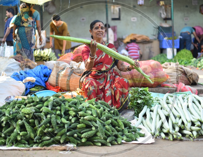 Vegetable Seller holding snake gourd at Local Market/Rythu Bazar
