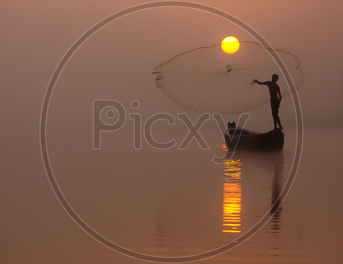 A fisher Man Fishing on Foggy Mornig With a Backdrop  Of Sun / Sunrise Fishing / Locals Fishing in India / Fisher Man Throwing Fishing Net