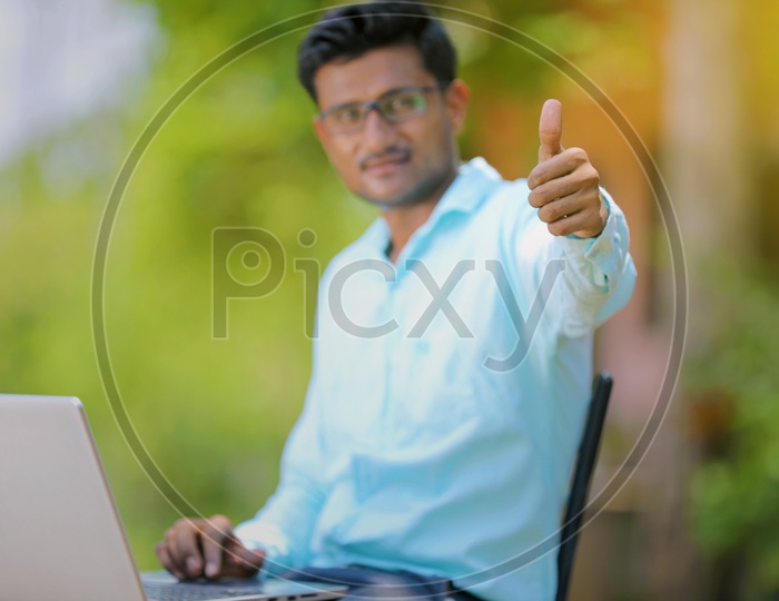 Indian College Student working on Laptop and showing Thumbs up