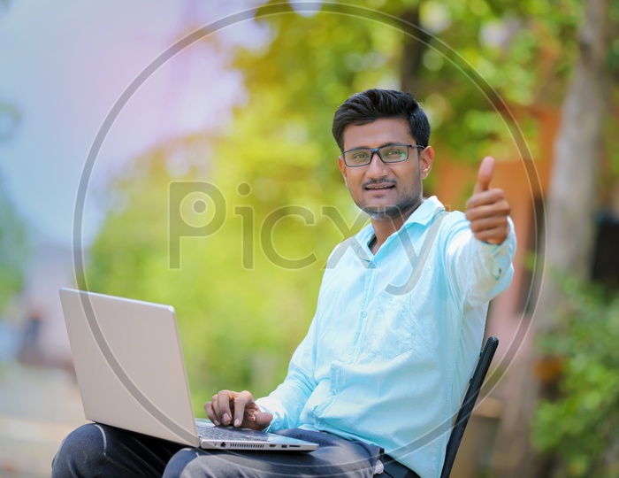 Indian College Student working on Laptop and showing Thumbs up
