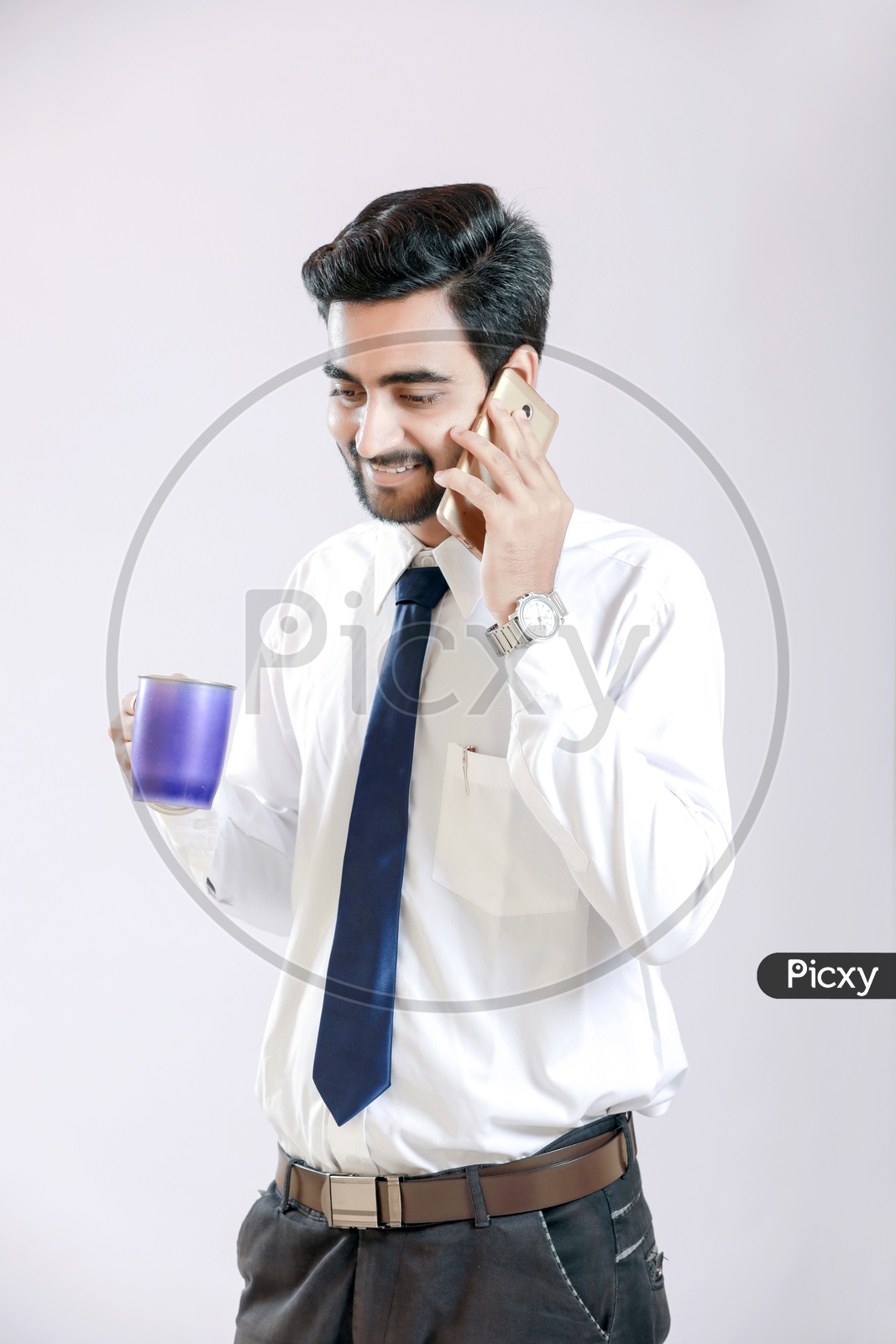 Young Indian Man talking on Smartphone and Holding Cup in Hand