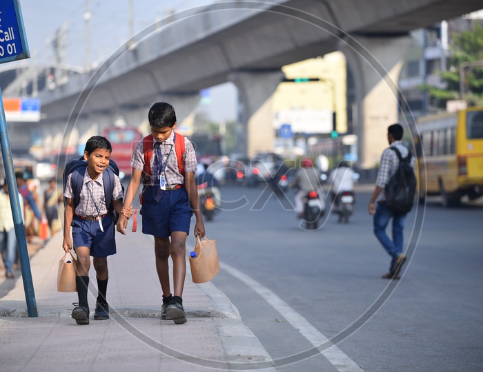 Children walking to school in the morning on a footpath of a busy road