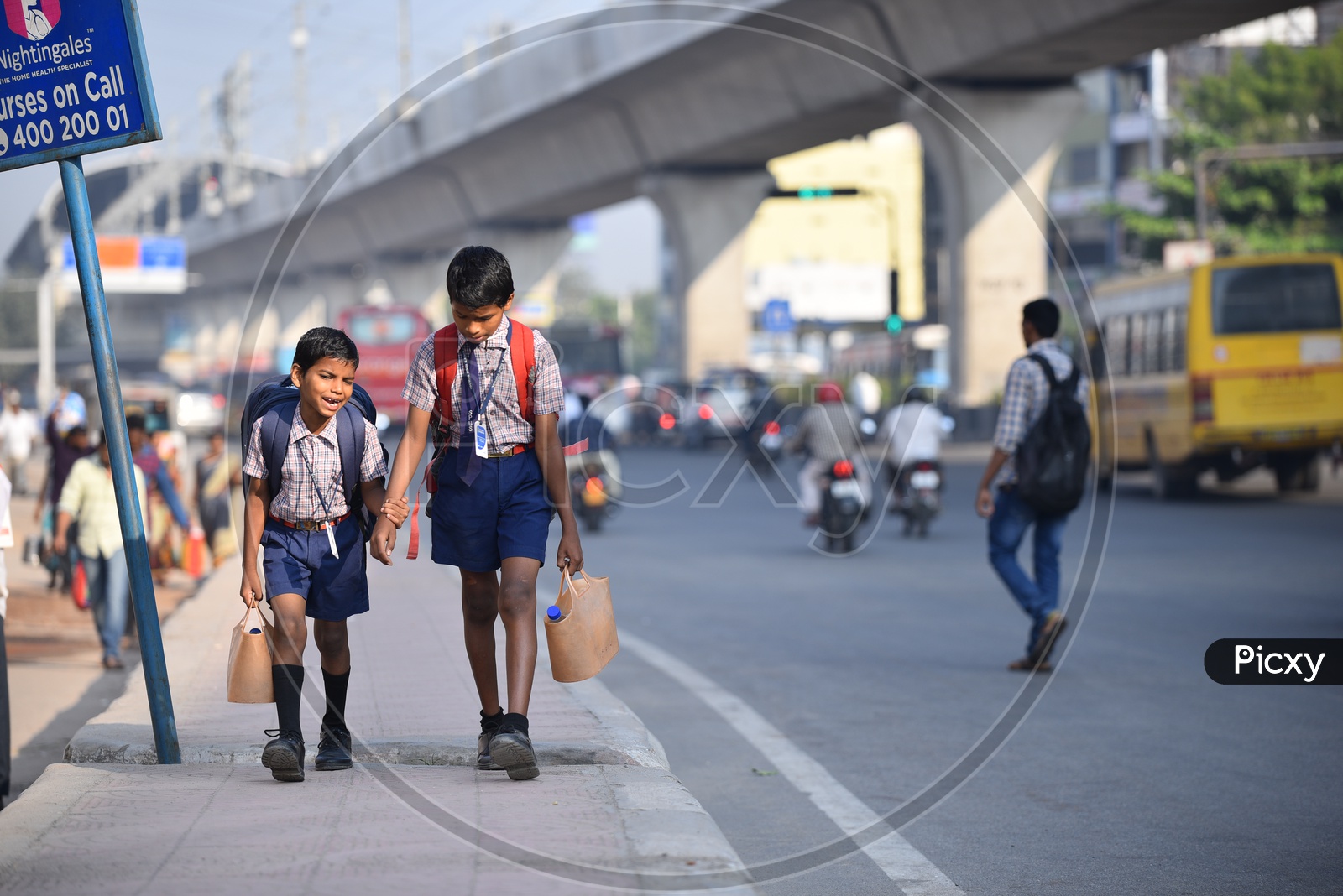 Children walking to school in the morning on a footpath of a busy road