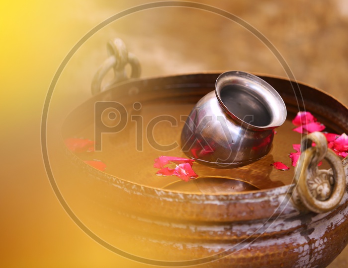 Water in Copper Tub with Rose petals which is Bath efore Wedding , Bridal Bath / Groom Bath in Traditional Hindu Wedding