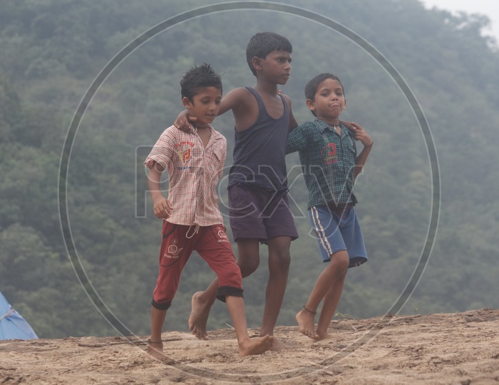 Three boys walking on the bank of river godavari.