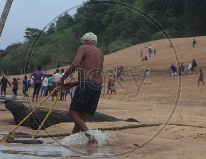 An Oldman Pulling the rope of a boat on the bank of river Godavari.