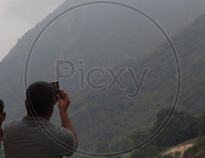 A Man capturing the view of papikondalu through his mobile.