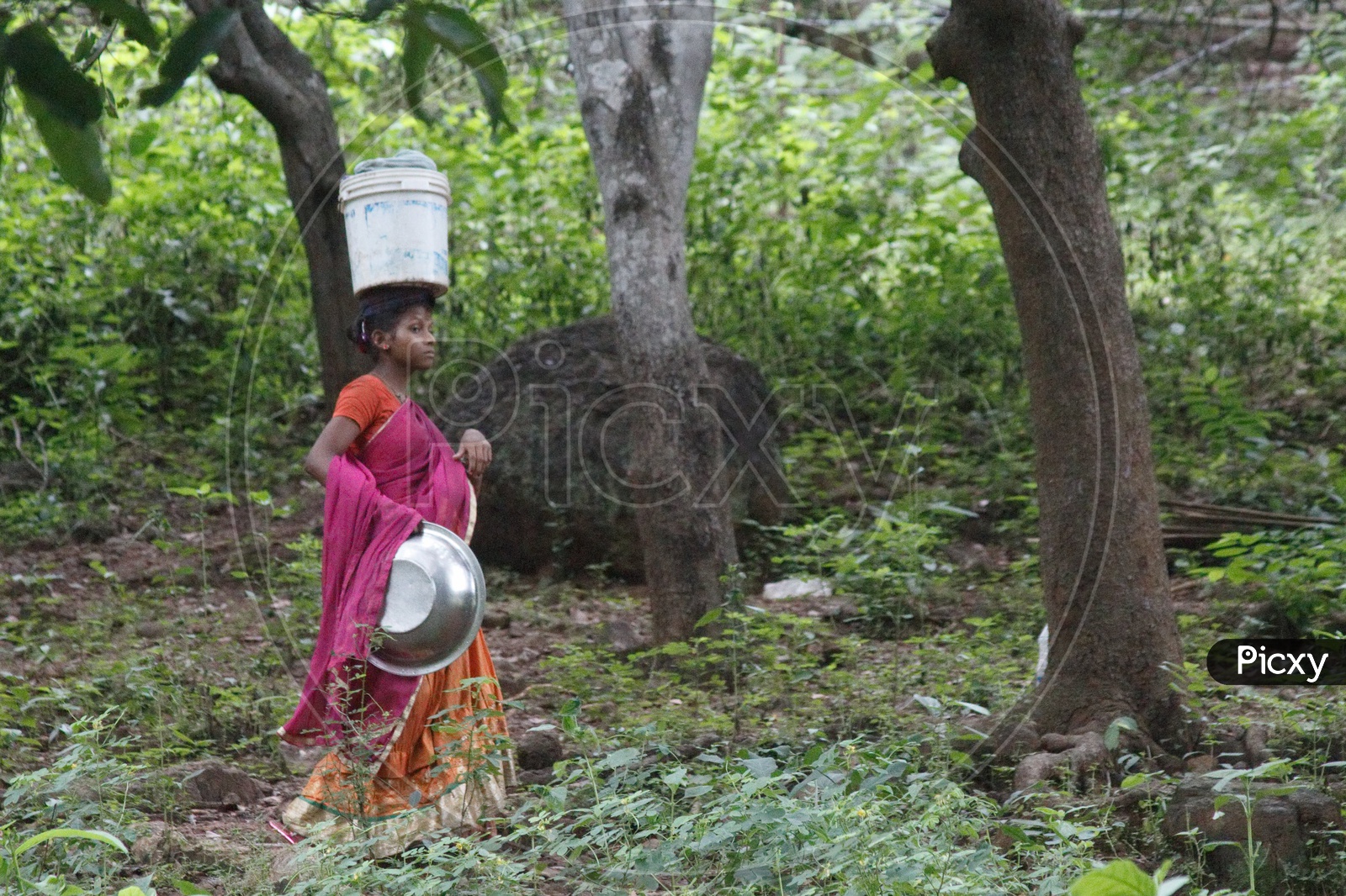 A woman carrying clothes in a bucket on her head.