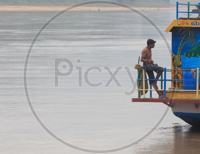 A man sitting on a boat sailing on river Godavari.