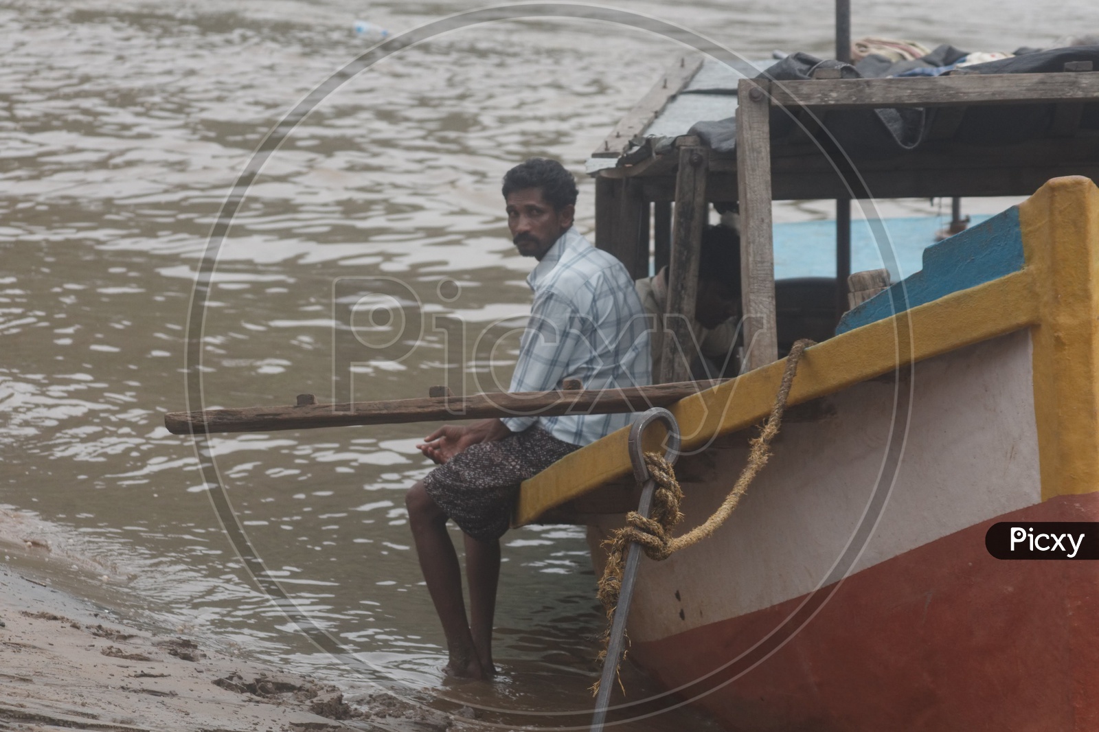 A Man Sitting on boat anchored at river godavari.