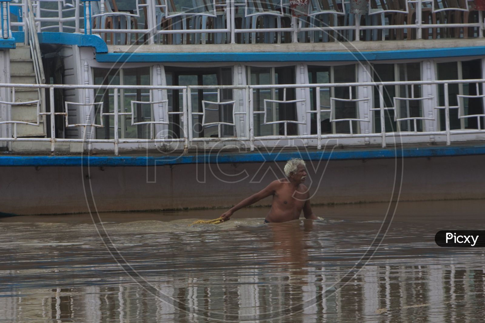 An Oldman Pulling the rope of a boat on the bank of river Godavari.
