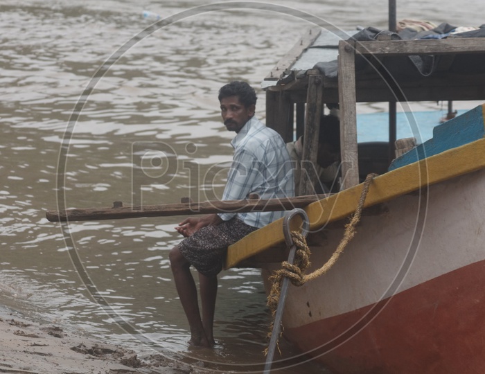 A Man Sitting on boat anchored at river godavari.