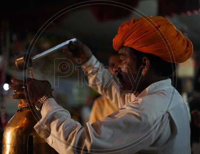 A Tea / Chai Vendor Filling Glass With Tea in Pushkar Camel Fair