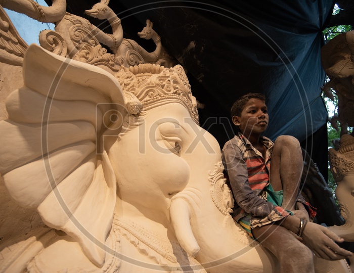 Small boy Sitting on Ganesh/Vigneshwara/Vinnayaka Idol