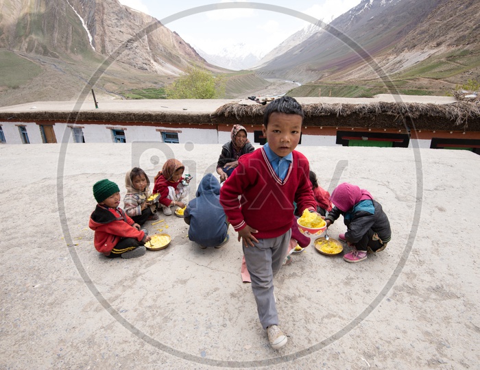 Kids having their food in Spiti Valley with Mountains in background