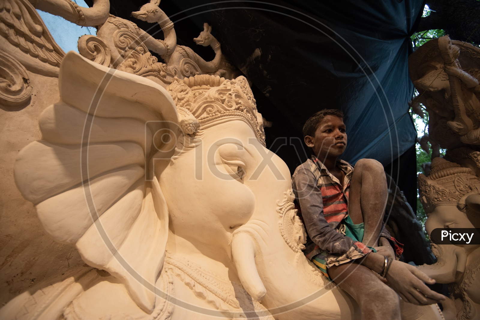 Small boy Sitting on Ganesh/Vigneshwara/Vinnayaka Idol