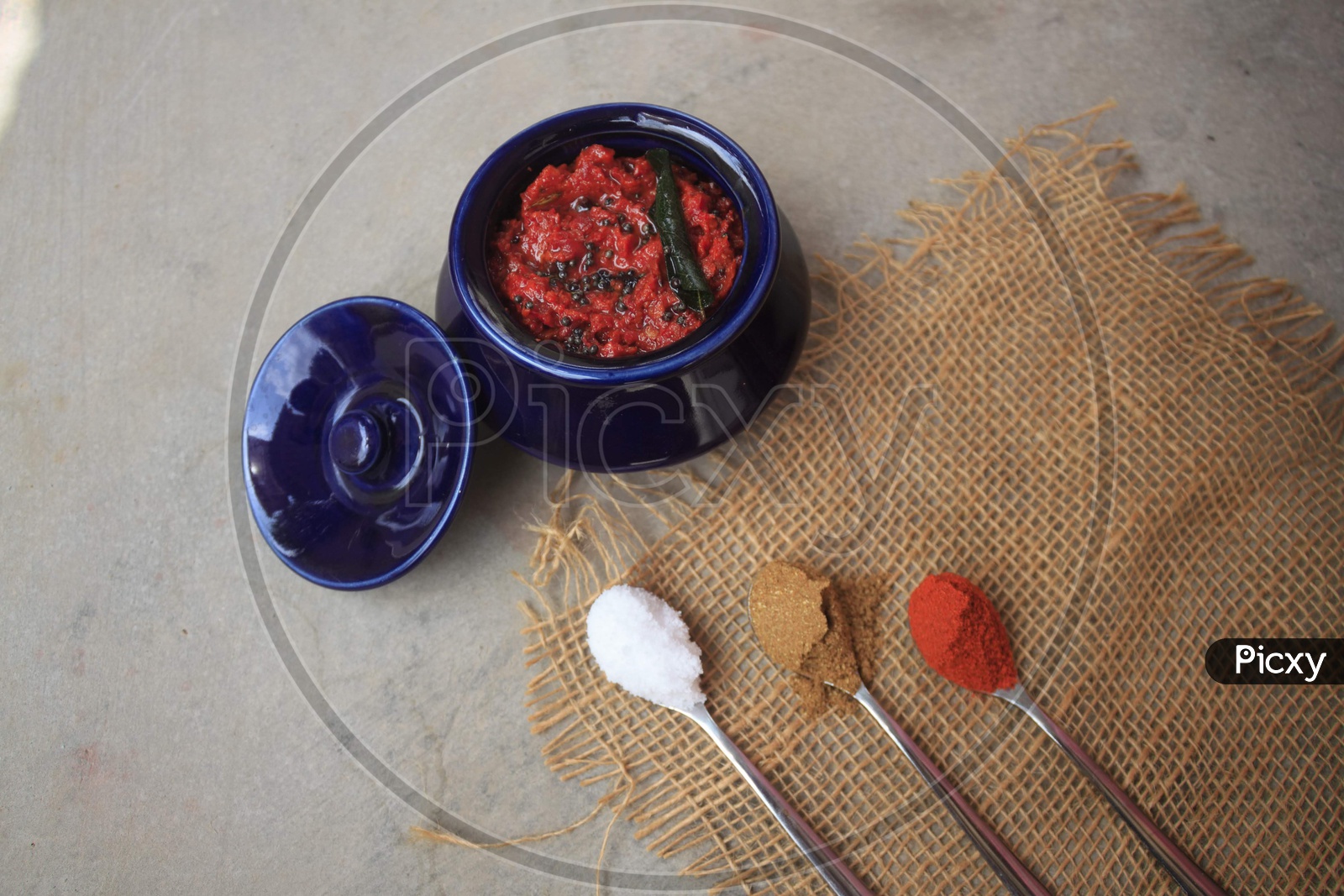Indian Homemade Tomato Pickle / Achar Composition Shot With Ingredients in Spoons Presentation