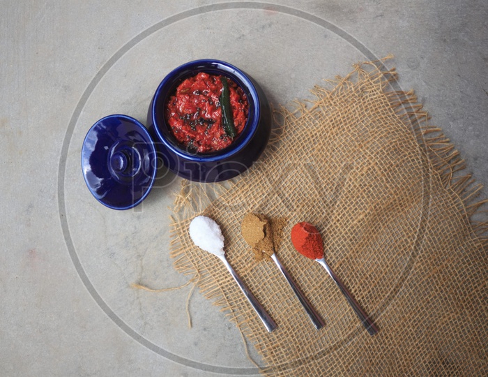 Indian Homemade Tomato Pickle / Achar  Composition Shot With Ingredients In Spoons  Presentation