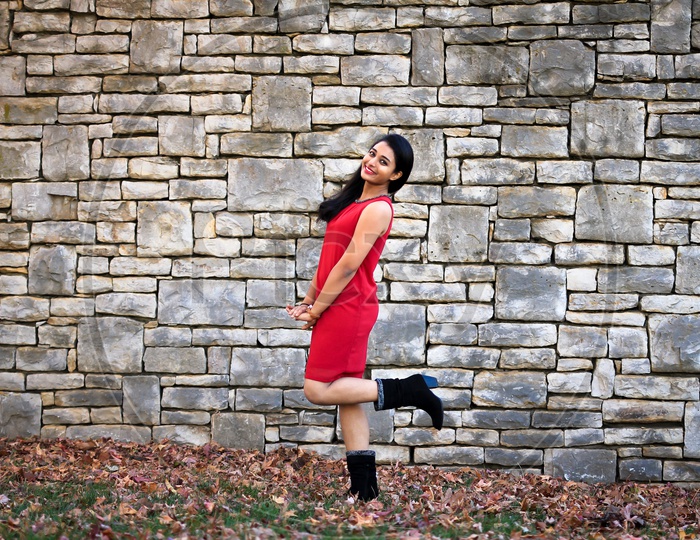 Female Model in red dress and Black boots - with blocked rock wall