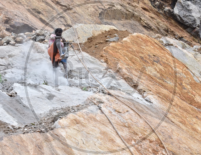 A Drilling Worker Working on a Hill With Stones  in Munnar