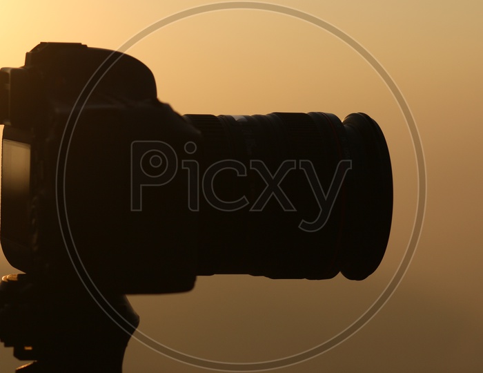 Silhouette Of a DSLR Camera Mounted To a Tripod  Over a Sunset