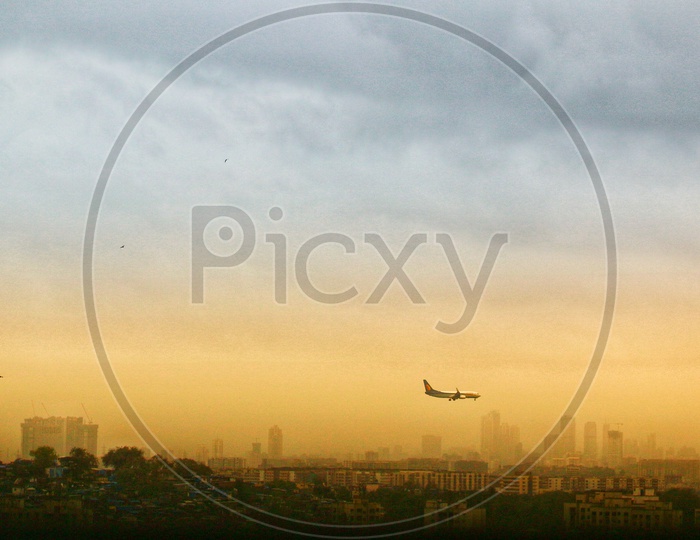 A Beautiful View Of a City and a Flight Landing with Golden Light In Sky with Clouds