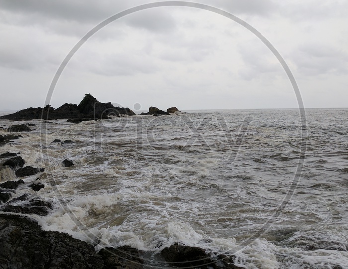 A View of Black Stones In Sea and The Waves Touching Those Stones Composition Shot