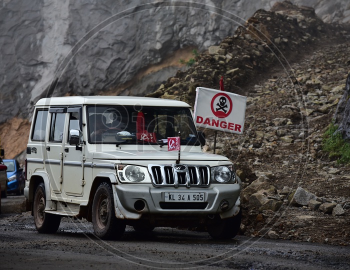A Jeep passes By a Road in Munnar With Danger Sign Showing on Beside The Road