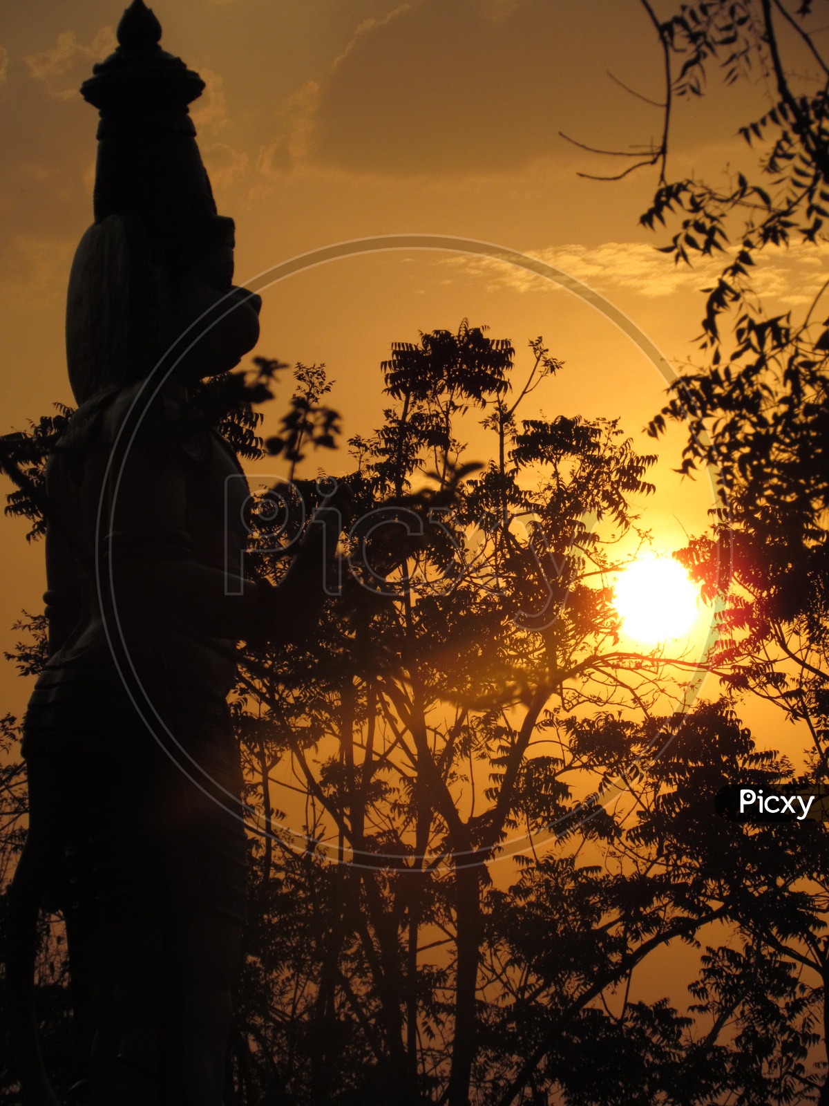 A Silhouette Of a Hanuman god Over a Golden Sun In Sky as background
