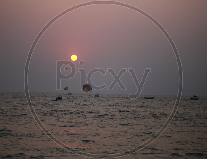 Paragliding and Speed boating Over a Sea with a Beautiful Sunset in Background