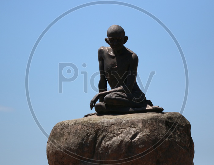 Mahatma Gandhi Statue On a Stone Over a Blue Sky Background