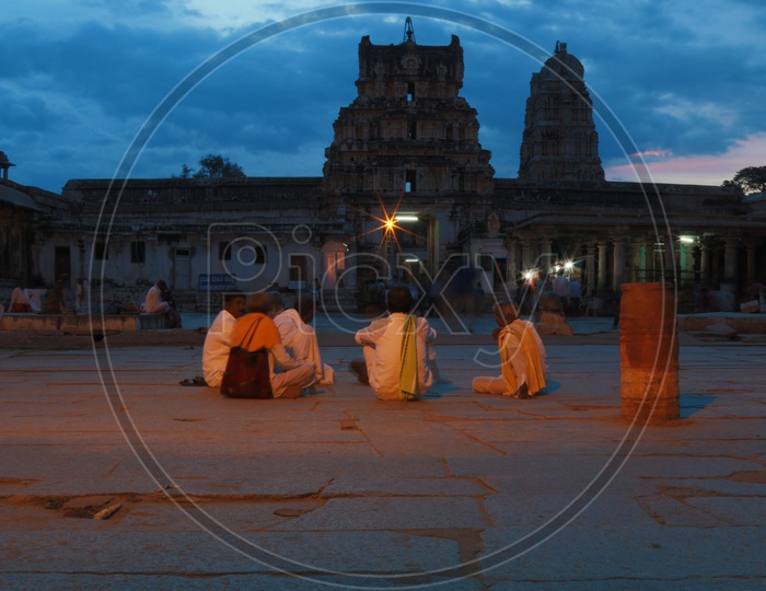 Devotees Siting in the temple Permises With temple Shrine Silhouette and Bluehour Sky as background