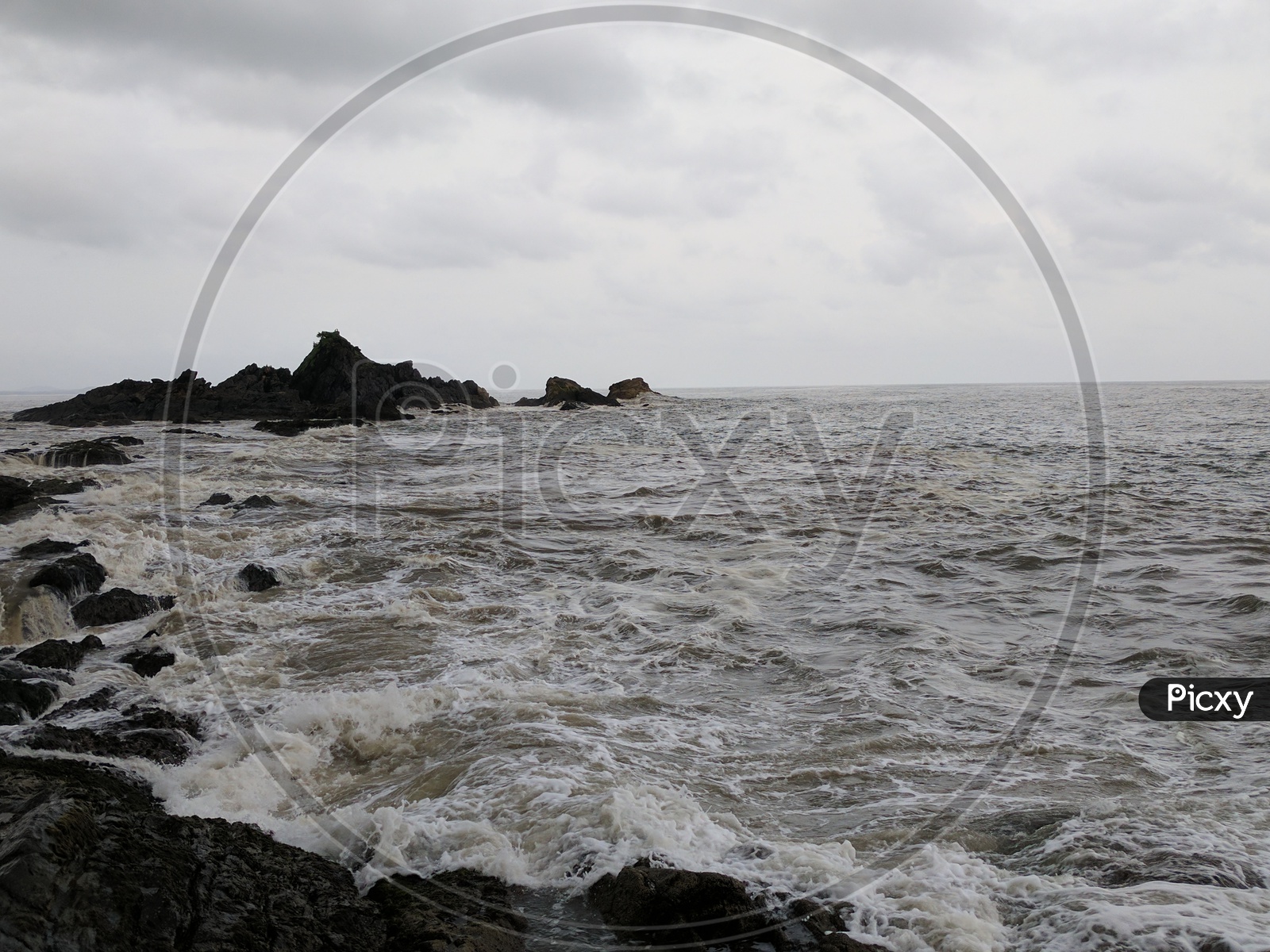 A View of Black Stones In Sea and The Waves Touching Those Stones Composition Shot
