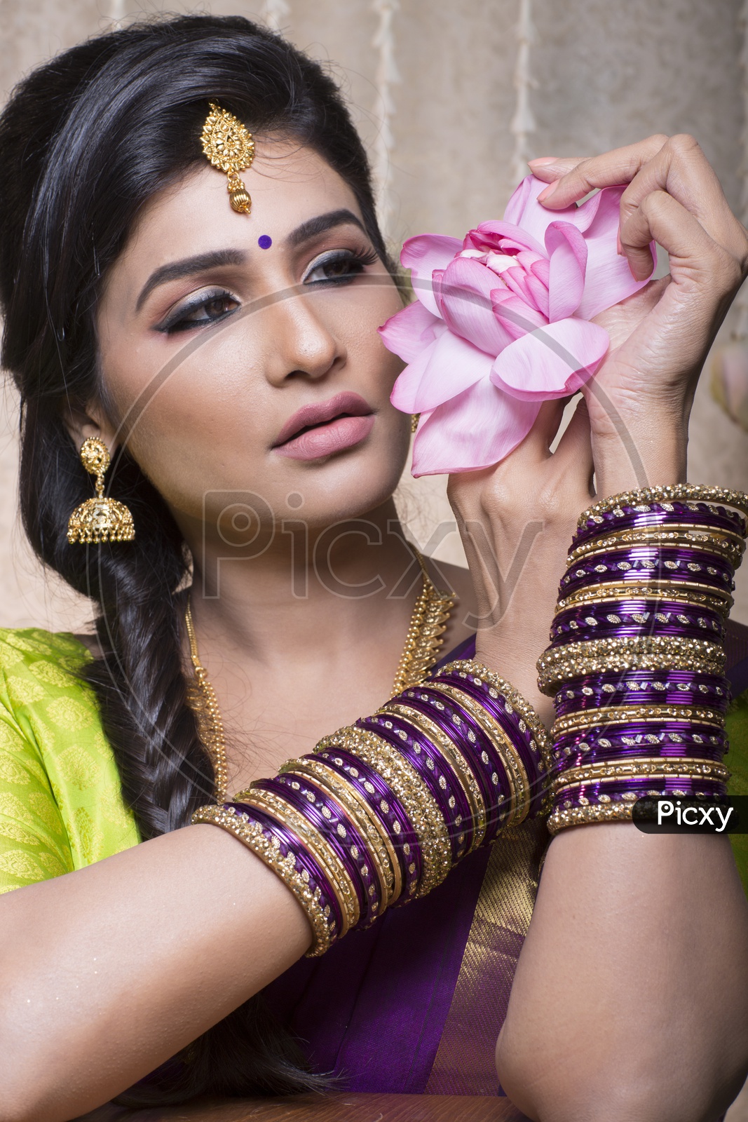 Traditional Indian Female/Woman Model in Purple Saree, green Blouse with a Lotus flower in hand - Smiling