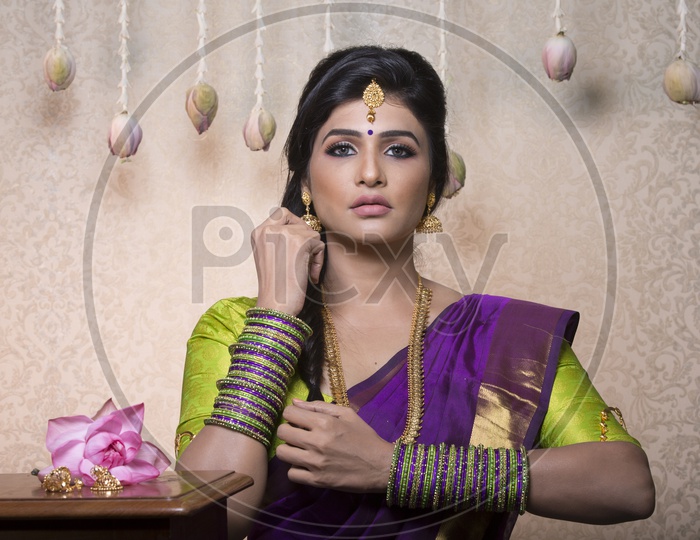 Traditional Indian Female/Woman Model in Purple Saree, green Blouse with a Lotus flower in hand - Posing
