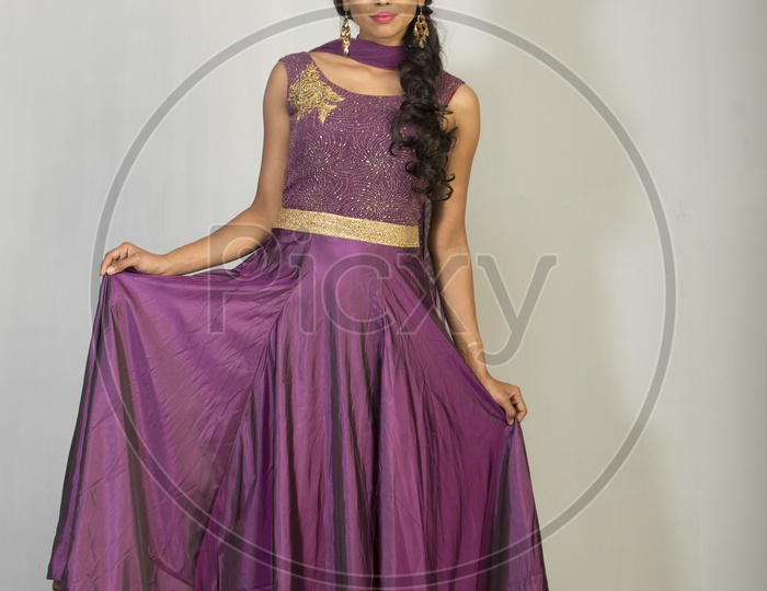 An Indian Female Model Wearing a Lavender  Chudidar Over  a Studio Setup and Smiling Looking to Camera