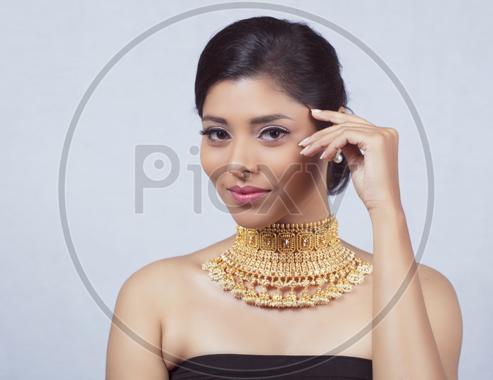 Indian Female Model With a Beautiful  Gold Necklace on Her Neck Looking To Camera And Smiling With An  Expression  On an Isolated White Background