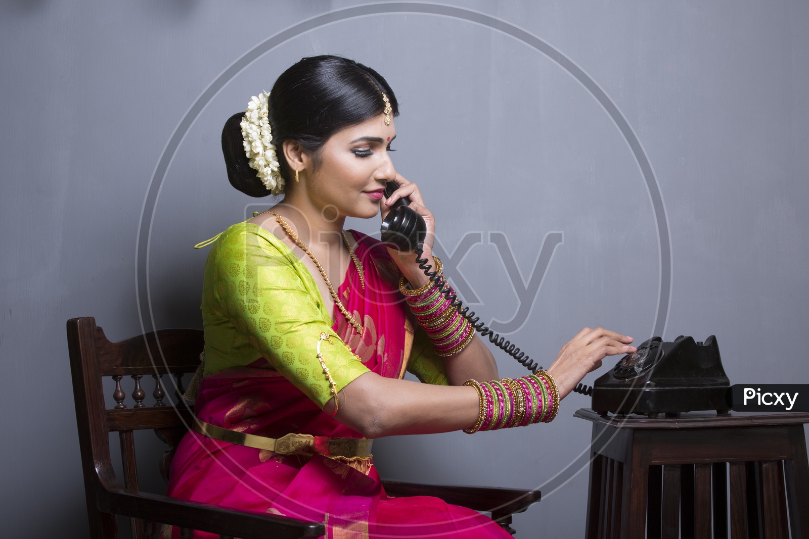 A Beautiful Indian Female Model  in Traditional Attire Wearing a Saree and Jewelry with an Expression and  Speaking in Phone on an Studio Closeup shot