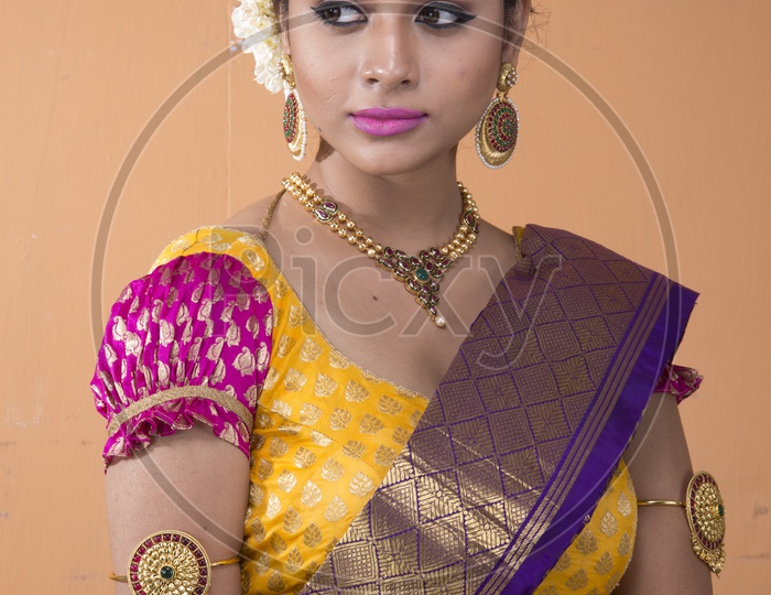 An Indian Female Model Wearing a Traditional Saree with Jewelry and Posing To Camera With Expression on an Isolated Background