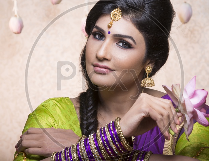 Traditional Indian Female/Woman Model in Purple Saree, green Blouse with a Lotus flower in hand