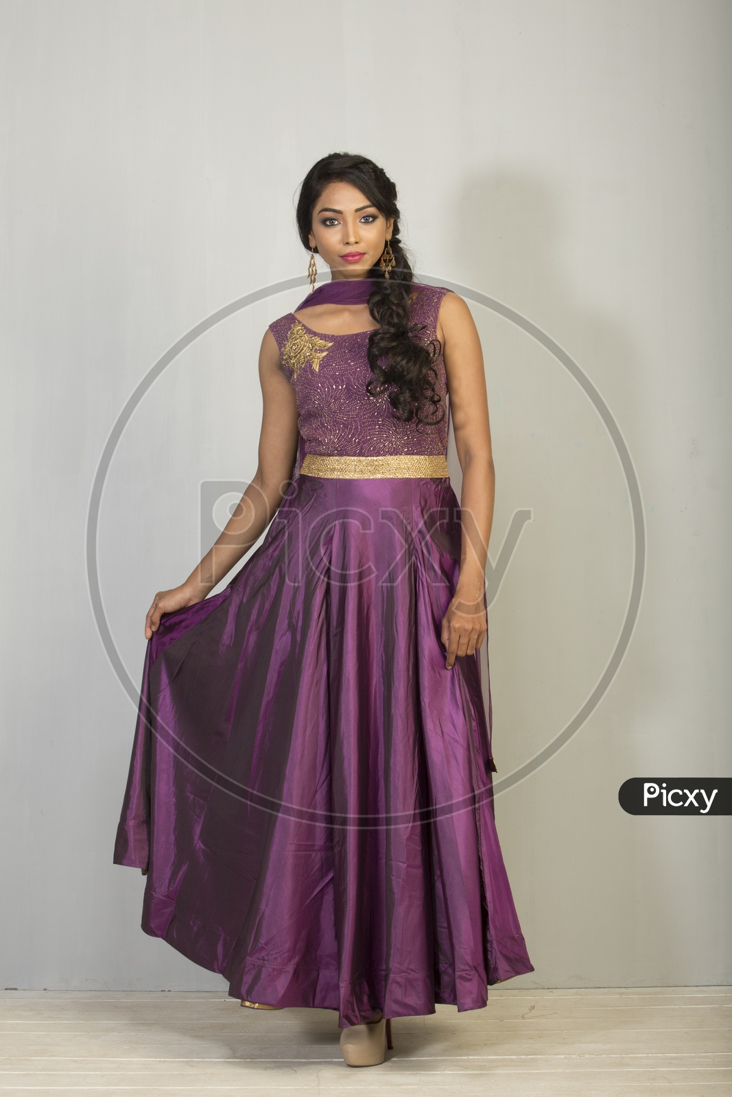 An Indian Female Model Wearing a Lavender  Chudidar Over  a Studio Setup and Smiling Looking to Camera