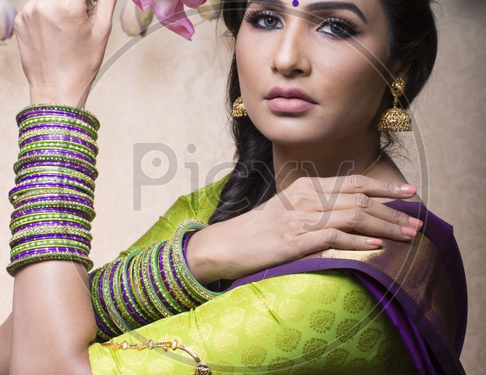 Traditional Indian Female/Woman Model in Purple Saree, green Blouse with a Lotus flower in hand