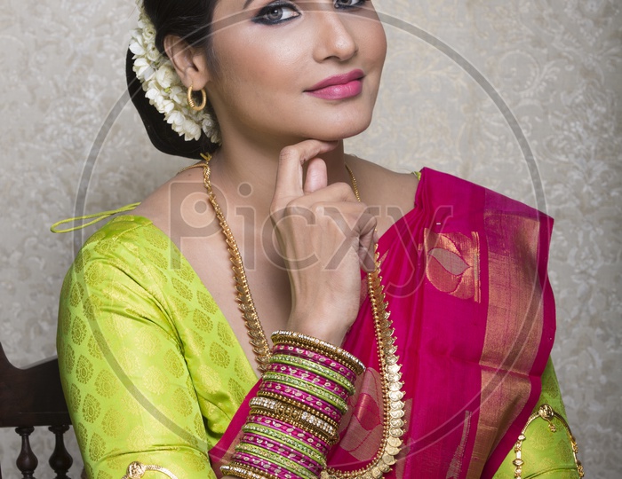 A Beautiful Indian Female Model  in Traditional Attire Wearing a Saree and Jewelry with an Expression  on an Studio Closeup shot